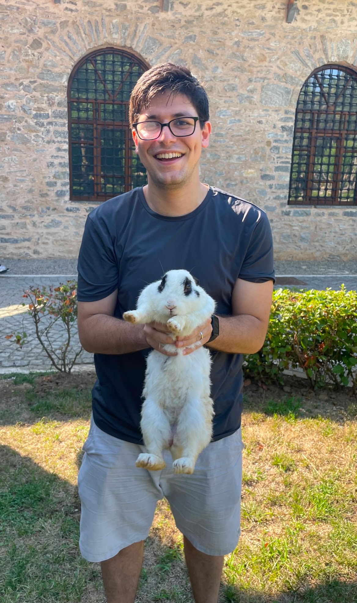 Metin Ersin Arıcan smiling while holding a white rabbit outdoors.
